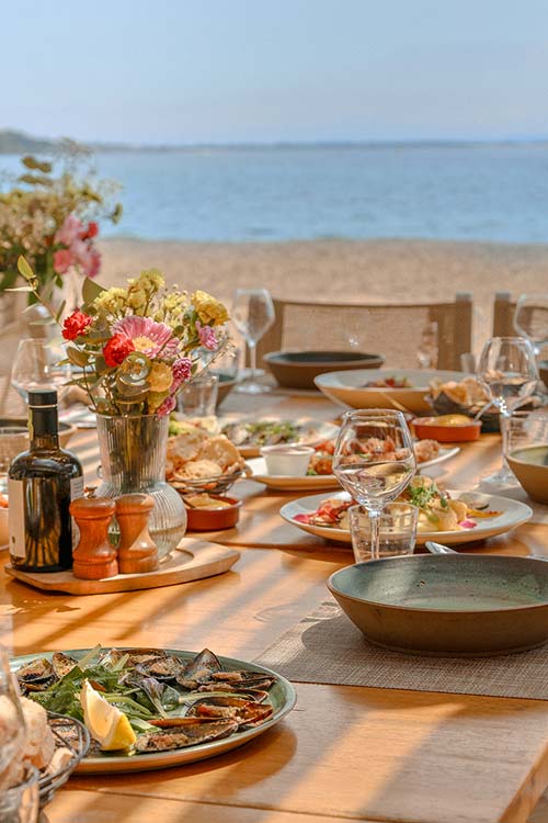 Restaurant de plage L'Aventure — Terrasse bord de mer, plage Péno, Carqueiranne Table dressée sur la terrasse du restaurant L'Aventure, vue sur la mer et les rochers de la plage Péno à Carqueiranne